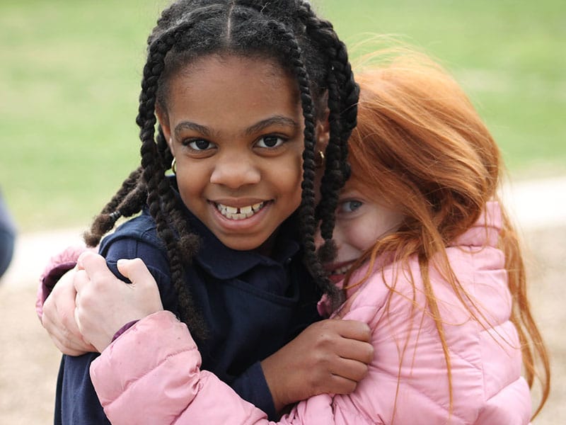 Two Grace Episcopal Day School students hugging each other