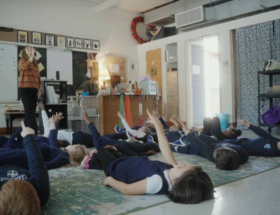 students laying on floor pointing at ceiling